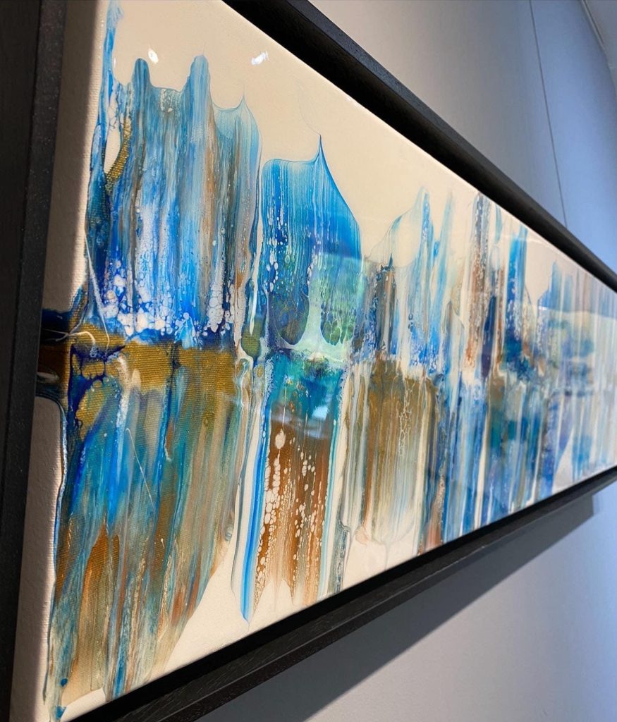 fluid acrylic swipe painting with various shades of blue and gold on a white background 